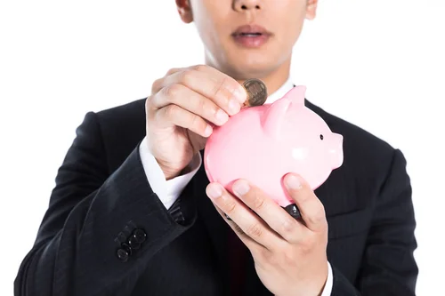 豚の貯金箱に500円を貯金しようとしている